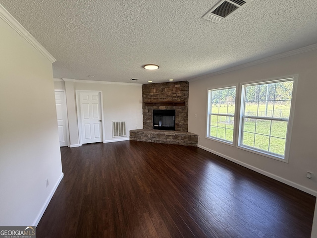 unfurnished living room featuring a stone fireplace, dark hardwood / wood-style flooring, ornamental molding, and a textured ceiling