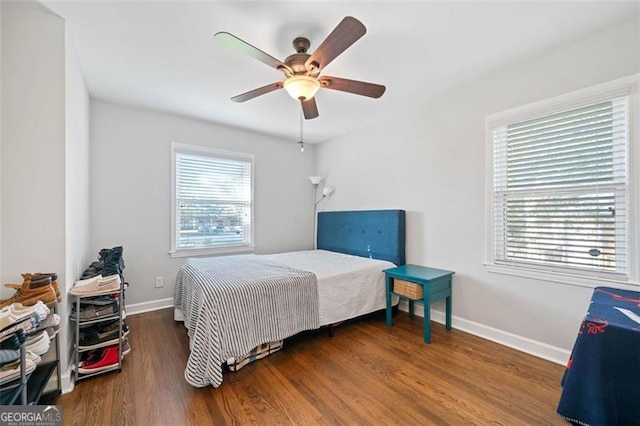 bedroom featuring dark hardwood / wood-style floors, ceiling fan, and multiple windows