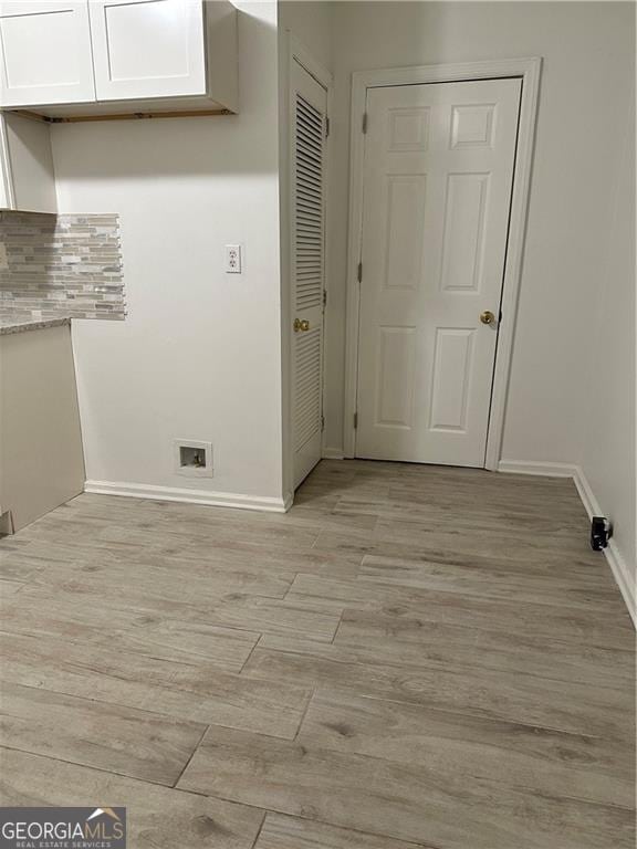 clothes washing area with hookup for a washing machine and light hardwood / wood-style flooring