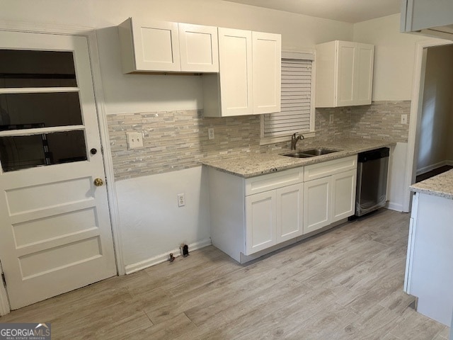 kitchen with white cabinets, dishwasher, light stone countertops, and light hardwood / wood-style flooring