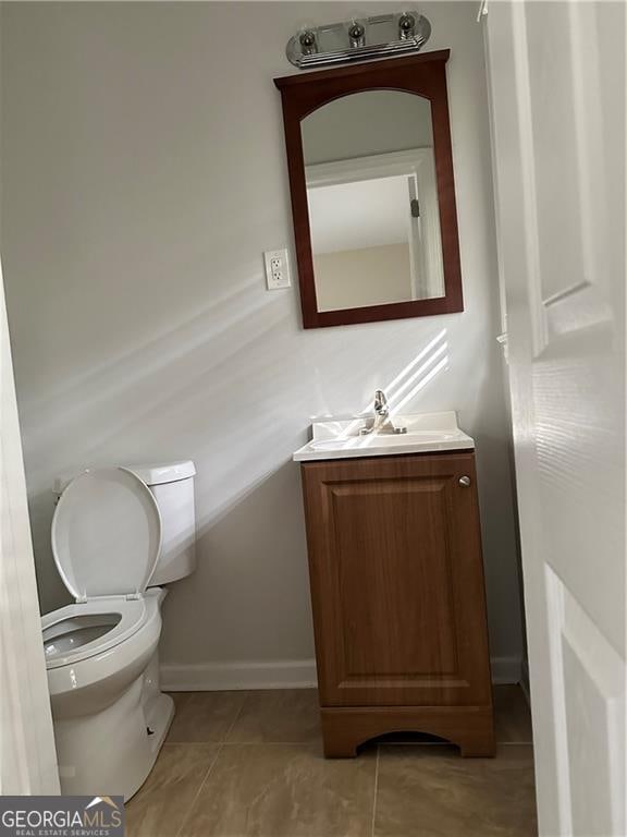 bathroom with toilet, vanity, and tile patterned floors