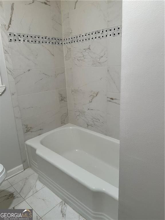 bathroom featuring tiled shower / bath combo and toilet