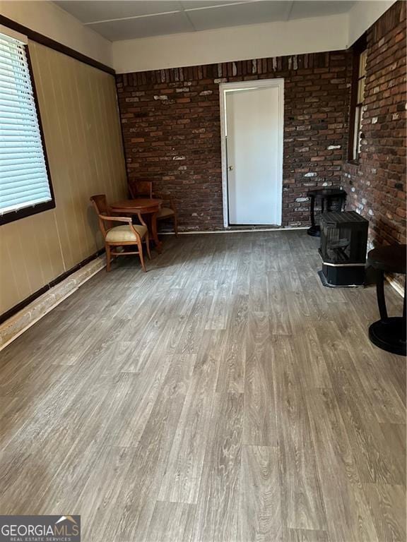 interior space with hardwood / wood-style flooring, a wood stove, and brick wall