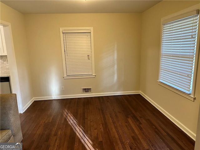 empty room with plenty of natural light and dark hardwood / wood-style flooring