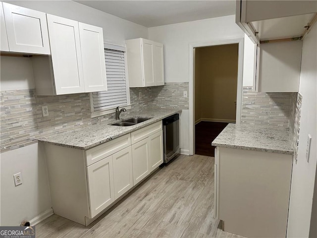 kitchen with sink, light hardwood / wood-style flooring, stainless steel dishwasher, decorative backsplash, and white cabinetry