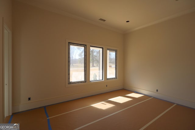 empty room with visible vents, baseboards, and crown molding