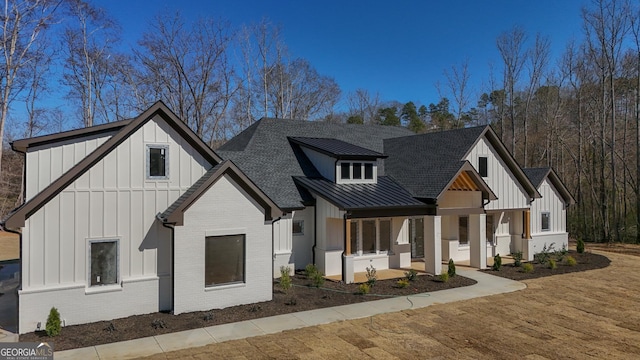 modern farmhouse style home with a standing seam roof, metal roof, board and batten siding, and brick siding