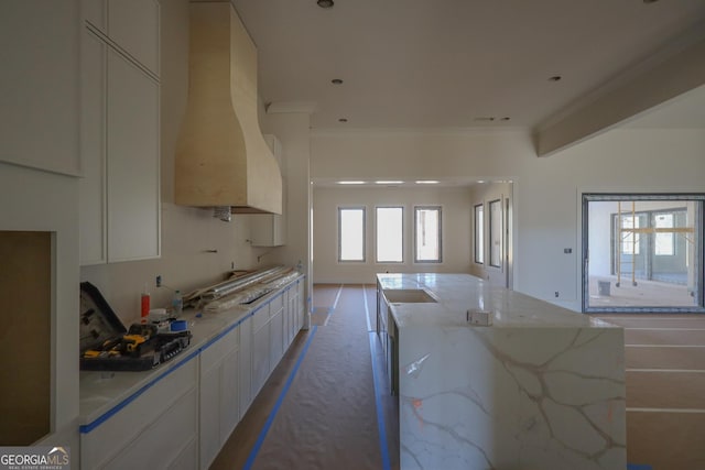 kitchen with a spacious island, white cabinetry, custom range hood, modern cabinets, and crown molding