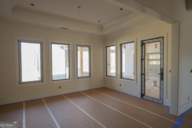 empty room featuring a raised ceiling, visible vents, and crown molding