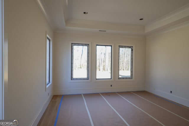 spare room with visible vents, baseboards, a raised ceiling, and ornamental molding