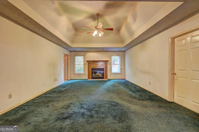 unfurnished living room featuring a raised ceiling, ceiling fan, and dark colored carpet