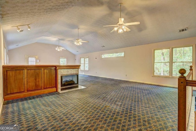 living room featuring a textured ceiling, dark carpet, lofted ceiling, and a premium fireplace