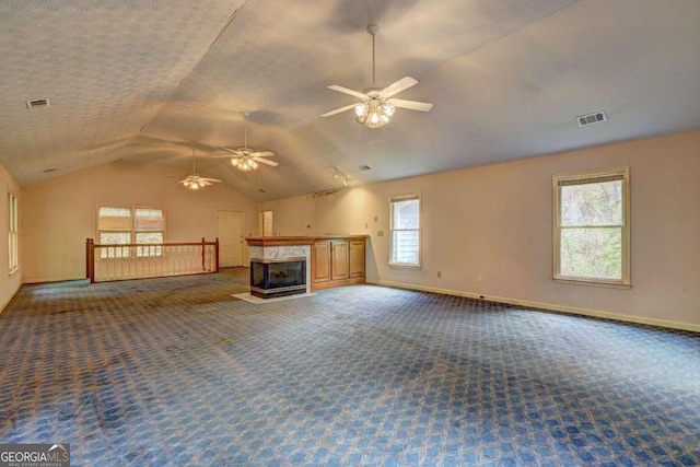 unfurnished living room featuring dark carpet, a textured ceiling, ceiling fan, a multi sided fireplace, and lofted ceiling