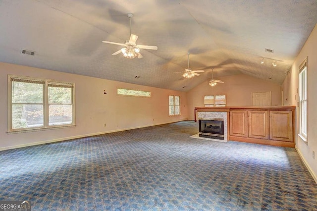 unfurnished living room featuring a high end fireplace, carpet floors, vaulted ceiling, and ceiling fan