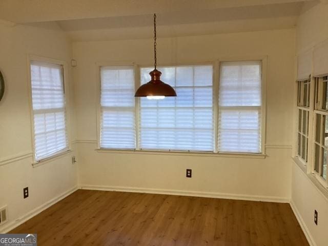 unfurnished dining area featuring a healthy amount of sunlight and dark wood-type flooring