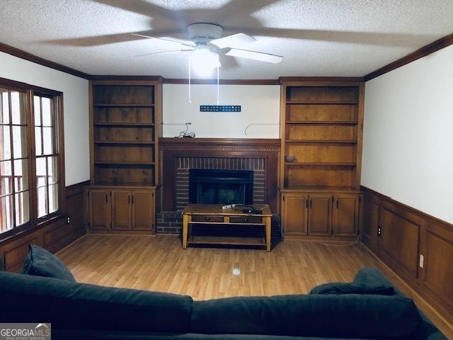 unfurnished living room with a textured ceiling, light hardwood / wood-style floors, and ornamental molding