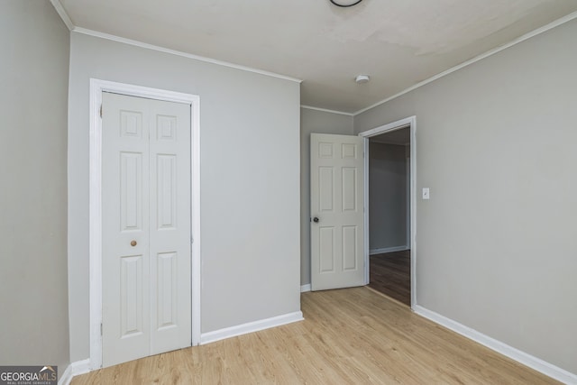 unfurnished bedroom with light hardwood / wood-style floors, crown molding, and a closet