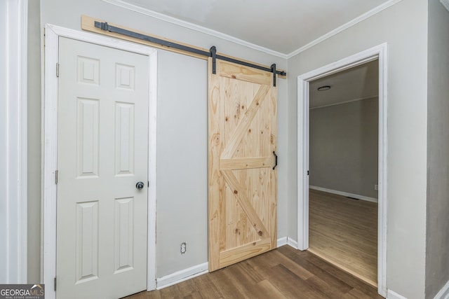unfurnished bedroom with a barn door, crown molding, a closet, and dark wood-type flooring