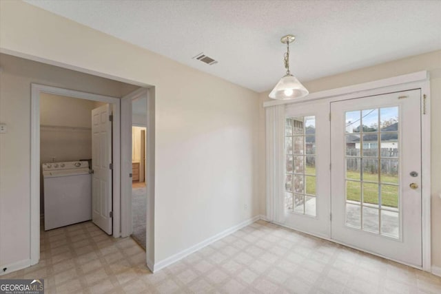 doorway with a textured ceiling and washer / dryer