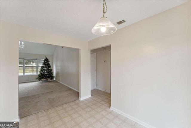 empty room with light carpet and a notable chandelier