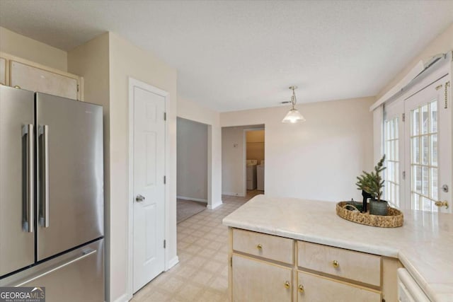 kitchen featuring high quality fridge, pendant lighting, light brown cabinets, dishwasher, and independent washer and dryer