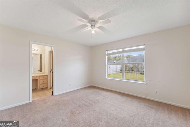 unfurnished bedroom with ensuite bath, ceiling fan, light colored carpet, and a textured ceiling