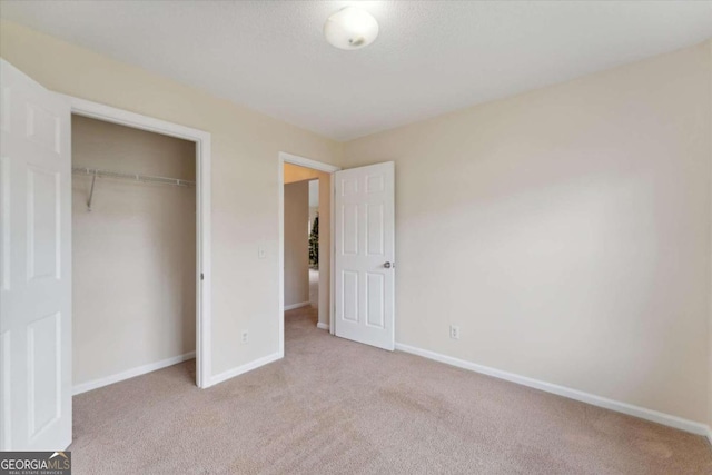 unfurnished bedroom featuring light colored carpet and a closet