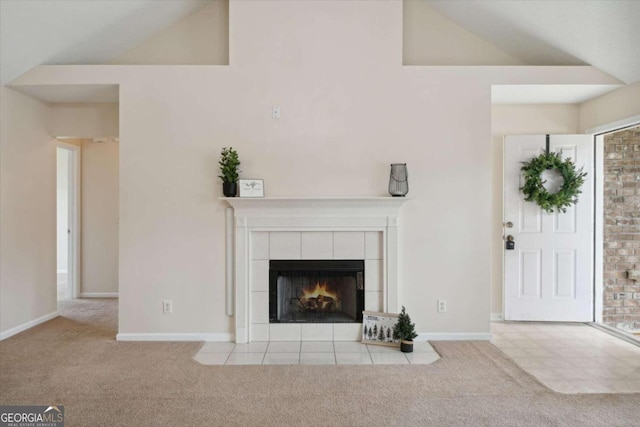 unfurnished living room featuring a tile fireplace, light carpet, and high vaulted ceiling