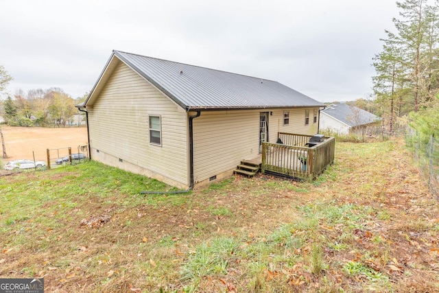 back of property featuring a wooden deck and a lawn