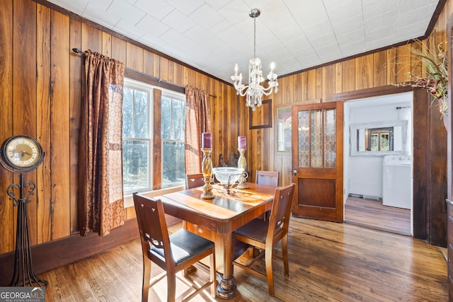 dining area featuring wood walls, hardwood / wood-style floors, washer / dryer, and crown molding