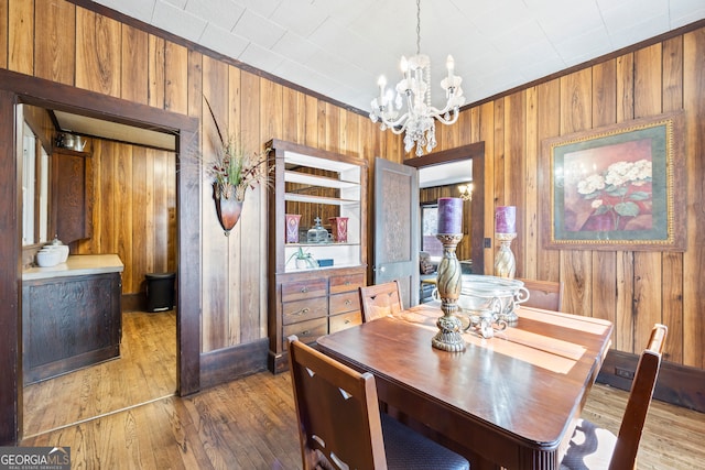 dining room featuring wood walls, a chandelier, and hardwood / wood-style flooring