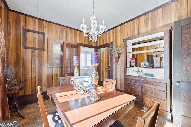 dining area with ornamental molding, light hardwood / wood-style flooring, an inviting chandelier, and wooden walls