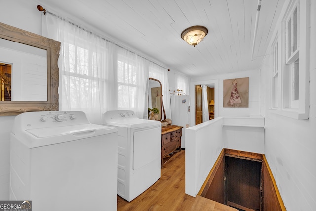 laundry area featuring water heater, wooden ceiling, independent washer and dryer, and light wood-type flooring