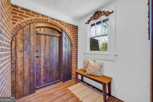 entryway featuring brick wall and light hardwood / wood-style floors