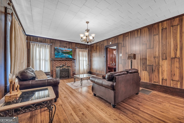 living room with a notable chandelier, a wealth of natural light, wood walls, and light hardwood / wood-style flooring