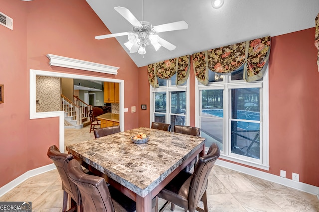 dining space with ceiling fan and high vaulted ceiling