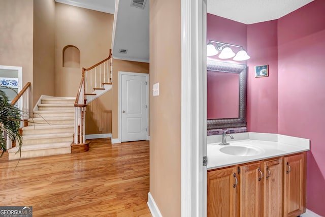 bathroom featuring hardwood / wood-style flooring, vanity, ornamental molding, and a textured ceiling