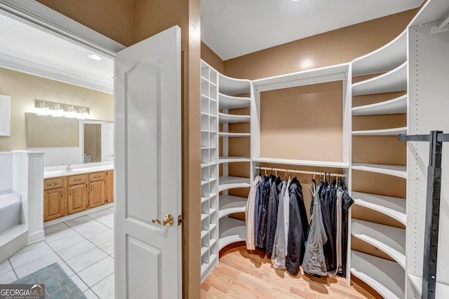 walk in closet with sink and light hardwood / wood-style flooring