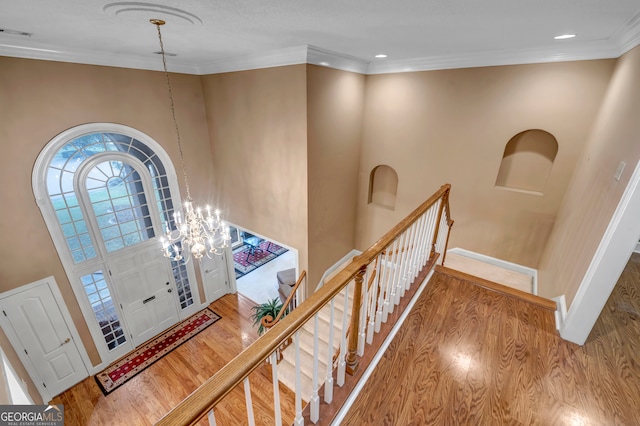 entrance foyer featuring ornamental molding, a chandelier, and hardwood / wood-style flooring