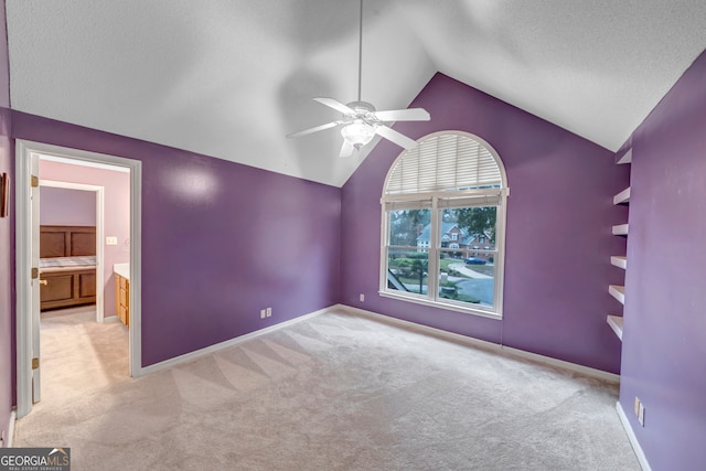 interior space with ceiling fan, light colored carpet, lofted ceiling, and a textured ceiling