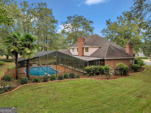 rear view of house featuring a lawn and glass enclosure