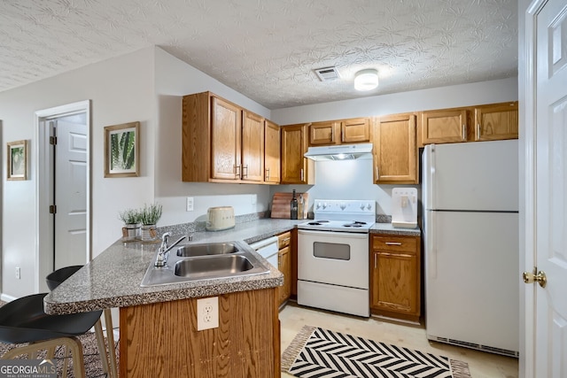 kitchen with sink, kitchen peninsula, a textured ceiling, white appliances, and a breakfast bar area