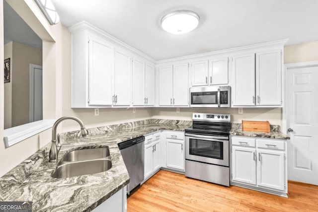 kitchen featuring white cabinetry, sink, dark stone counters, and appliances with stainless steel finishes