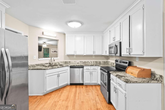 kitchen featuring stainless steel appliances, white cabinetry, sink, and dark stone counters