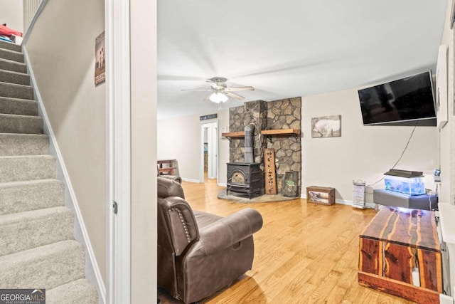 living room featuring a wood stove, hardwood / wood-style floors, and ceiling fan