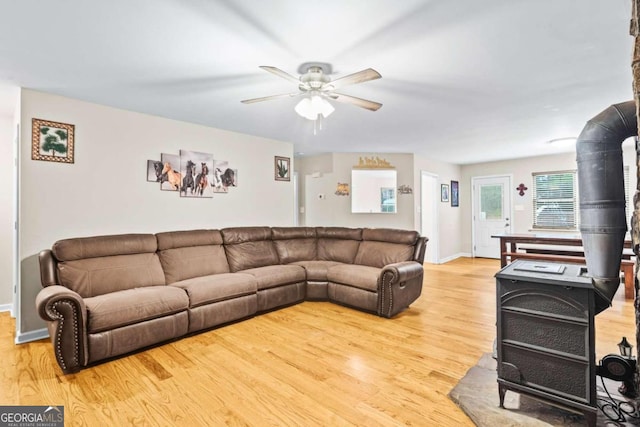 living room featuring hardwood / wood-style flooring, ceiling fan, and a wood stove