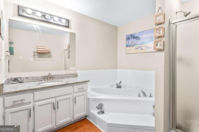 bathroom with hardwood / wood-style flooring, vanity, and plus walk in shower