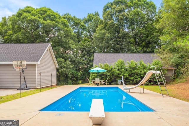 view of swimming pool featuring a patio, a diving board, and a water slide