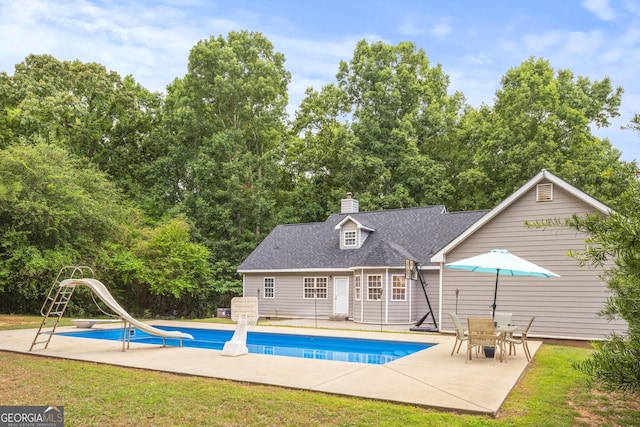 view of swimming pool with a water slide, an outdoor structure, a patio, and a lawn