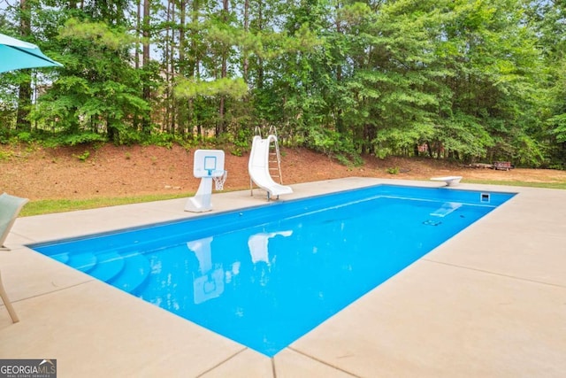 view of pool featuring a patio, a diving board, and a water slide